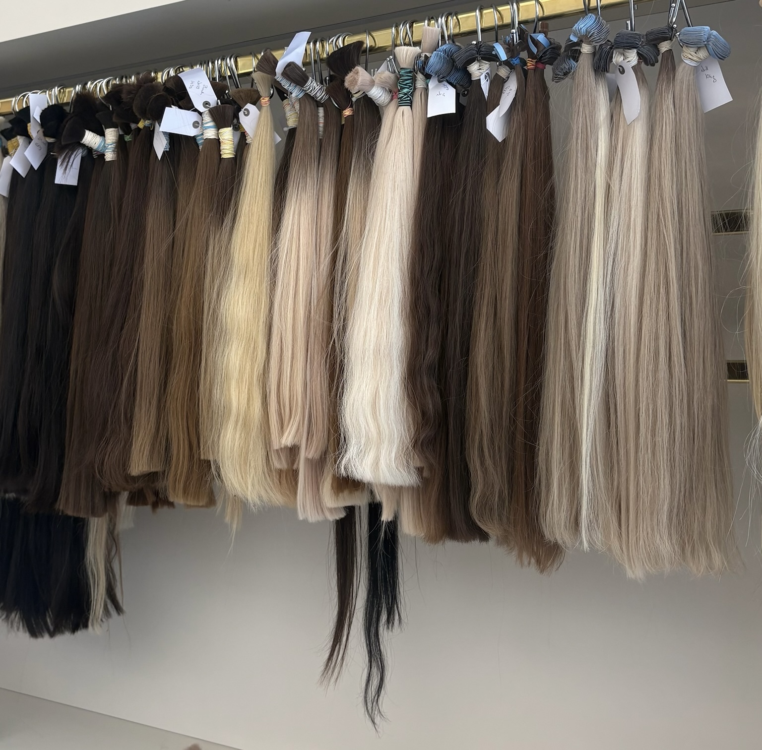 Custom-matched hair extension wefts and micro-ring beads laid out on a wooden board at Malibu Hair UK Exeter